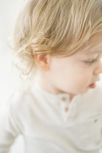 Close up of 2 year olds blonde curls, in all white studio by NYC Family Photography