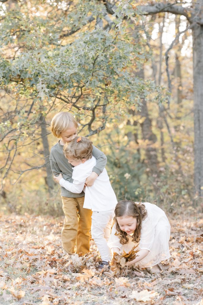 siblings hugging and playing in the fall leaves by NYC Family Photographer
