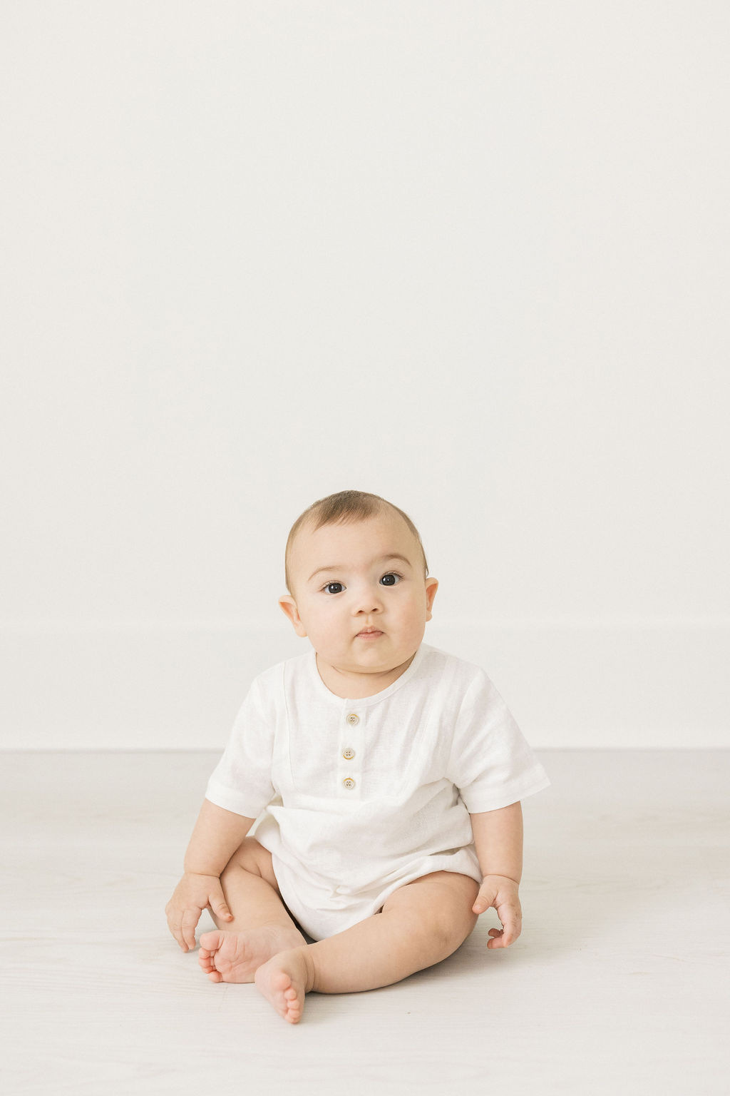 toddler sits on the floor of a studio in a while henley shirt montclair baby