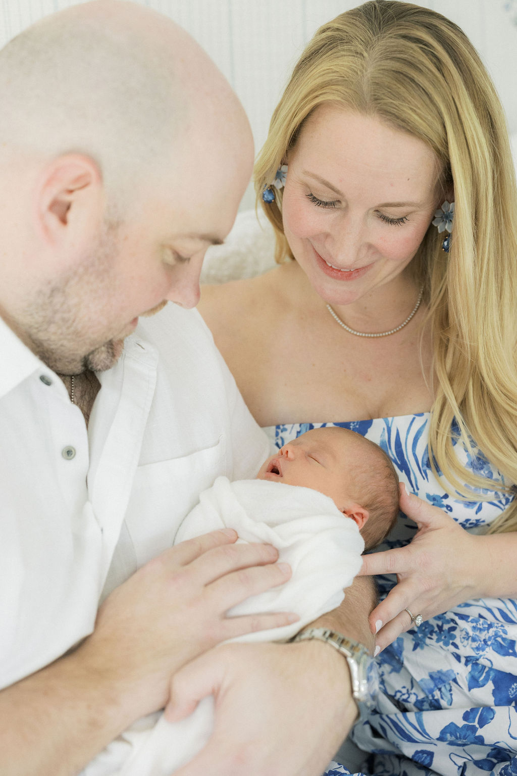 A father holds his newborn baby in his arms while mom leans in lactation central