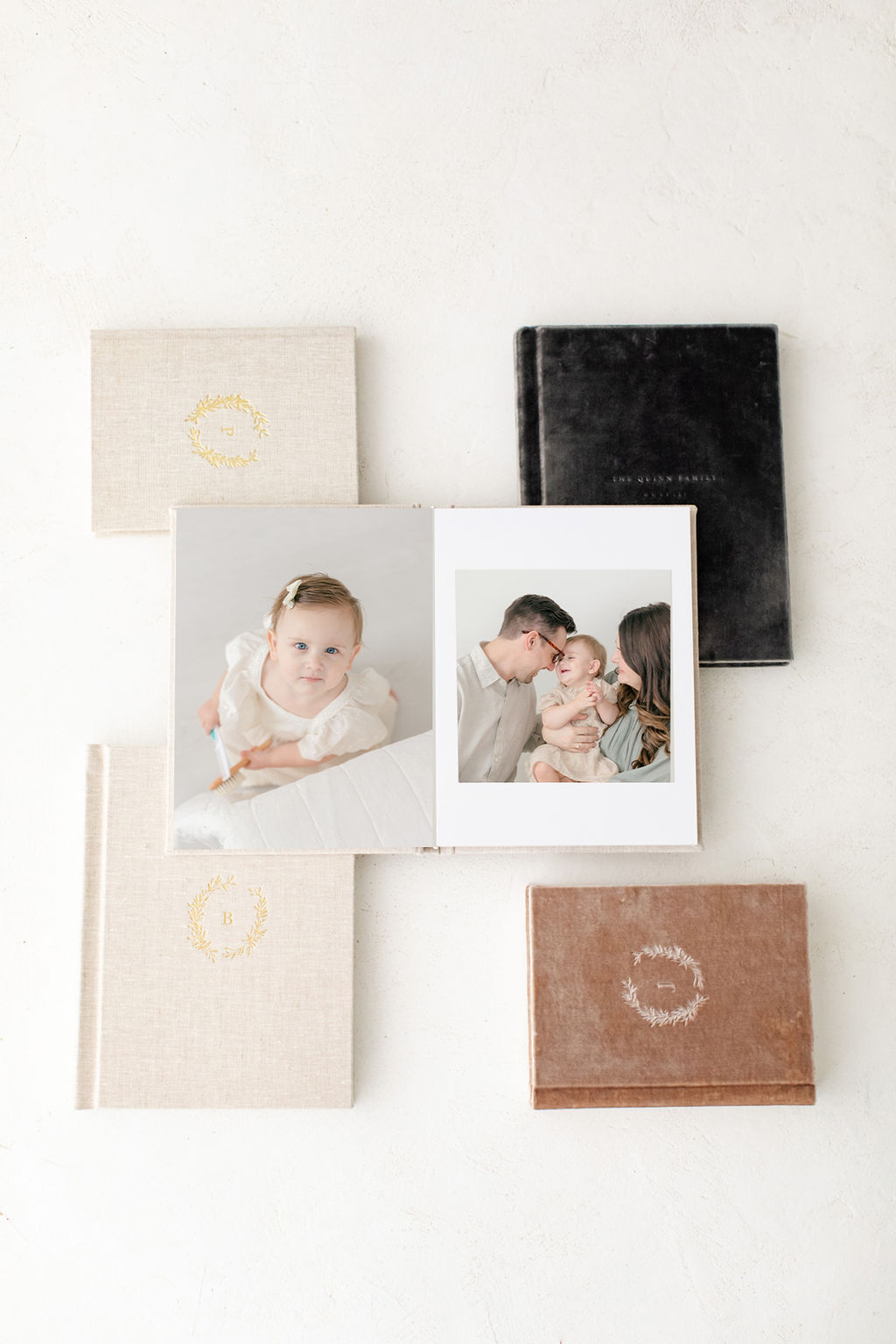 Five linen albums sitting on a table with one open to fine art photography prints
