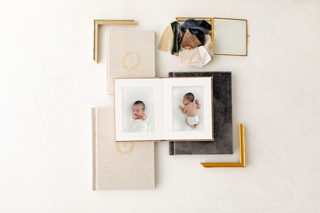 Gold and wood frame samples sit on a table with albums, album cover swatches and fine art photography prints