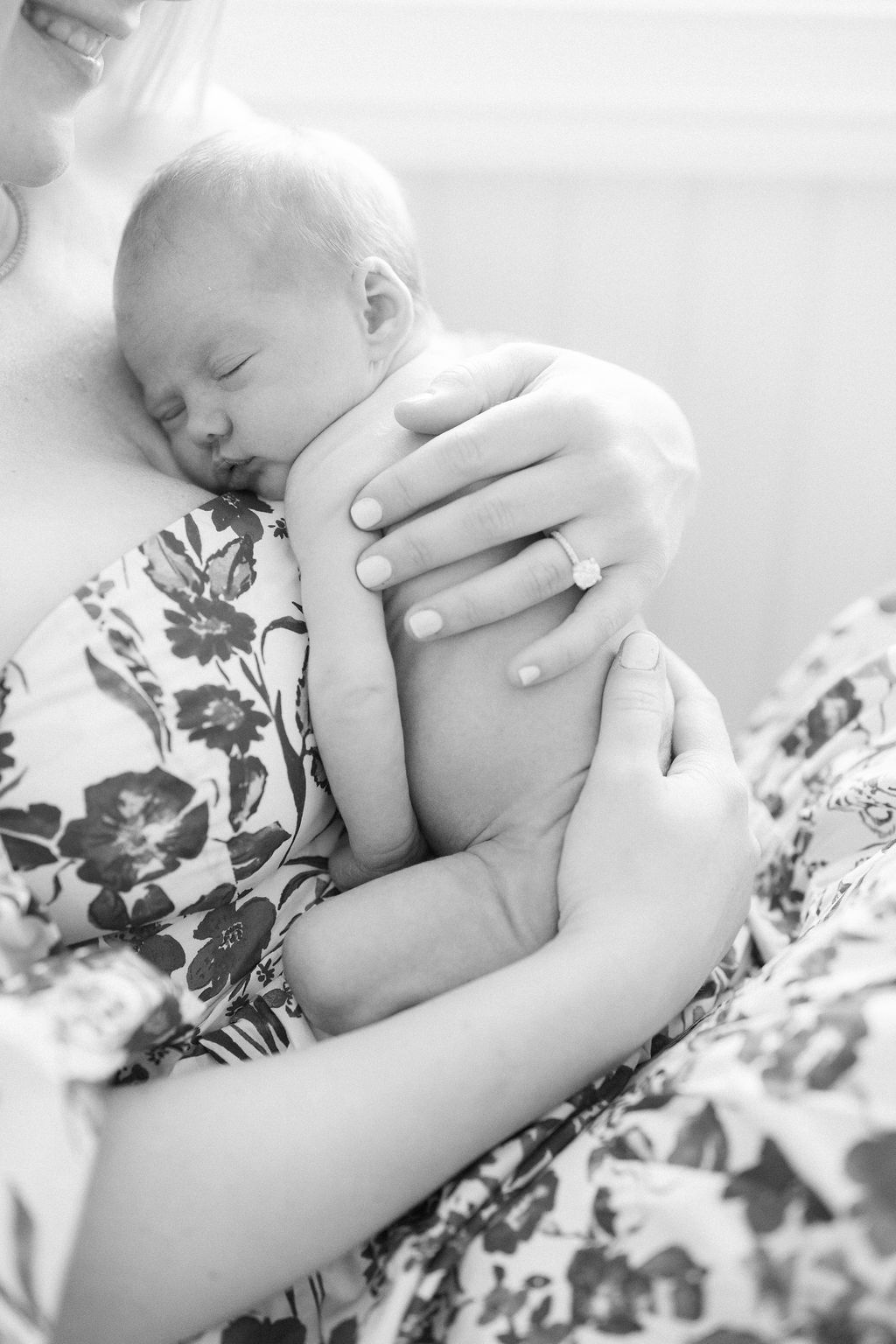 A newborn baby sleeps on mom's chest in a studio